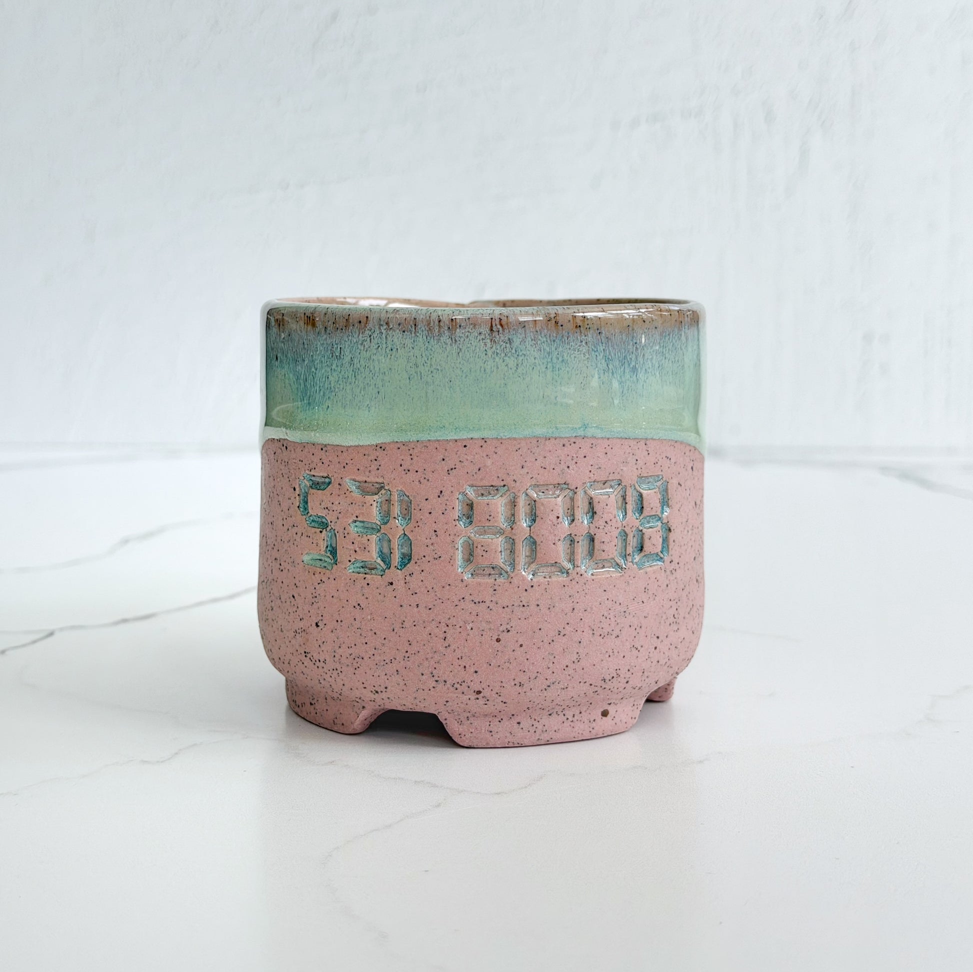 A handmade pink speckled clay ceramic cup by Kathleen Kalish Ceramics with mint green glaze. Stamped with 5318008. For the Boobless Project helping breast cancer.