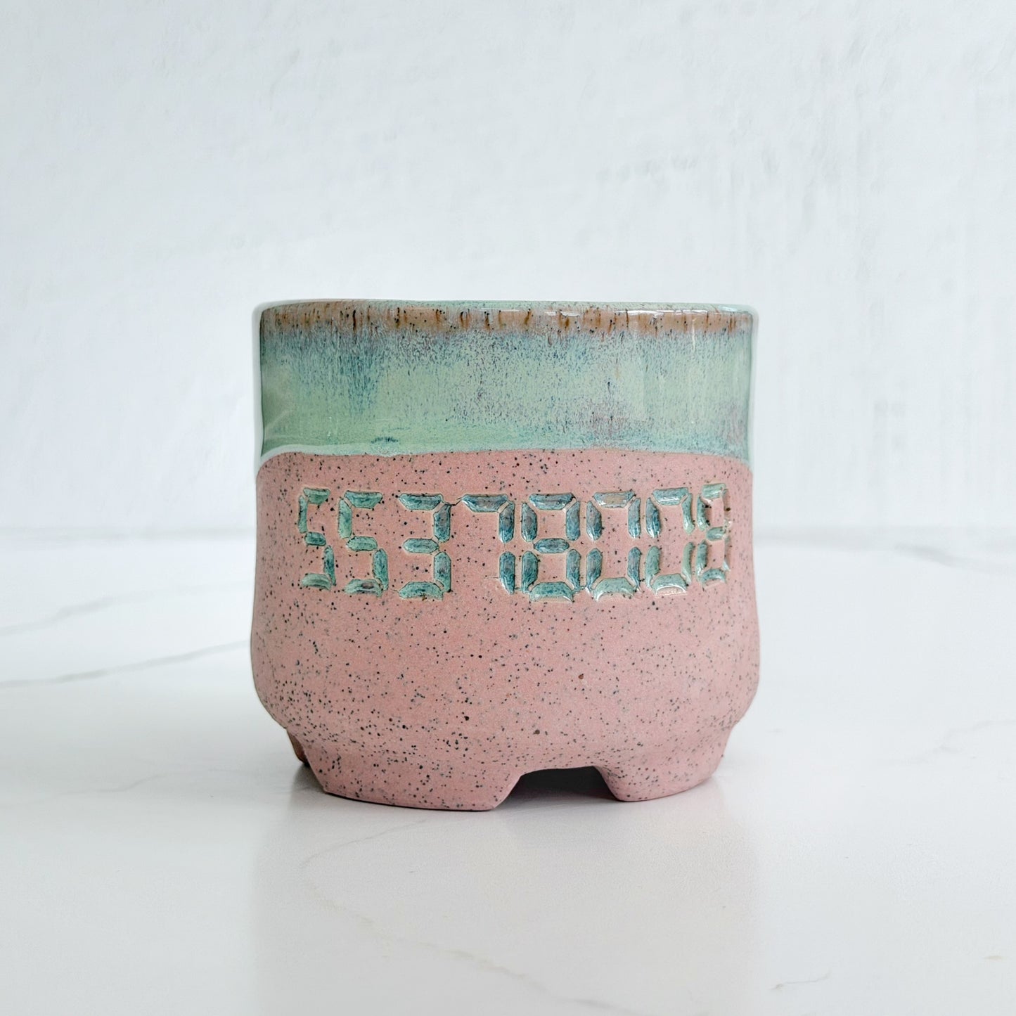 A handmade pink speckled clay ceramic cup by Kathleen Kalish Ceramics with mint green glaze. Stamped with 55378008. For the Boobless Project helping breast cancer.