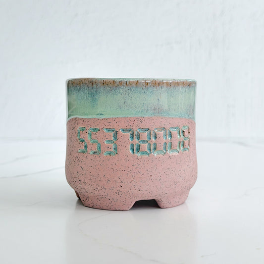 A handmade pink speckled clay ceramic cup by Kathleen Kalish Ceramics with mint green glaze. Stamped with 55378008. For the Boobless Project helping breast cancer.