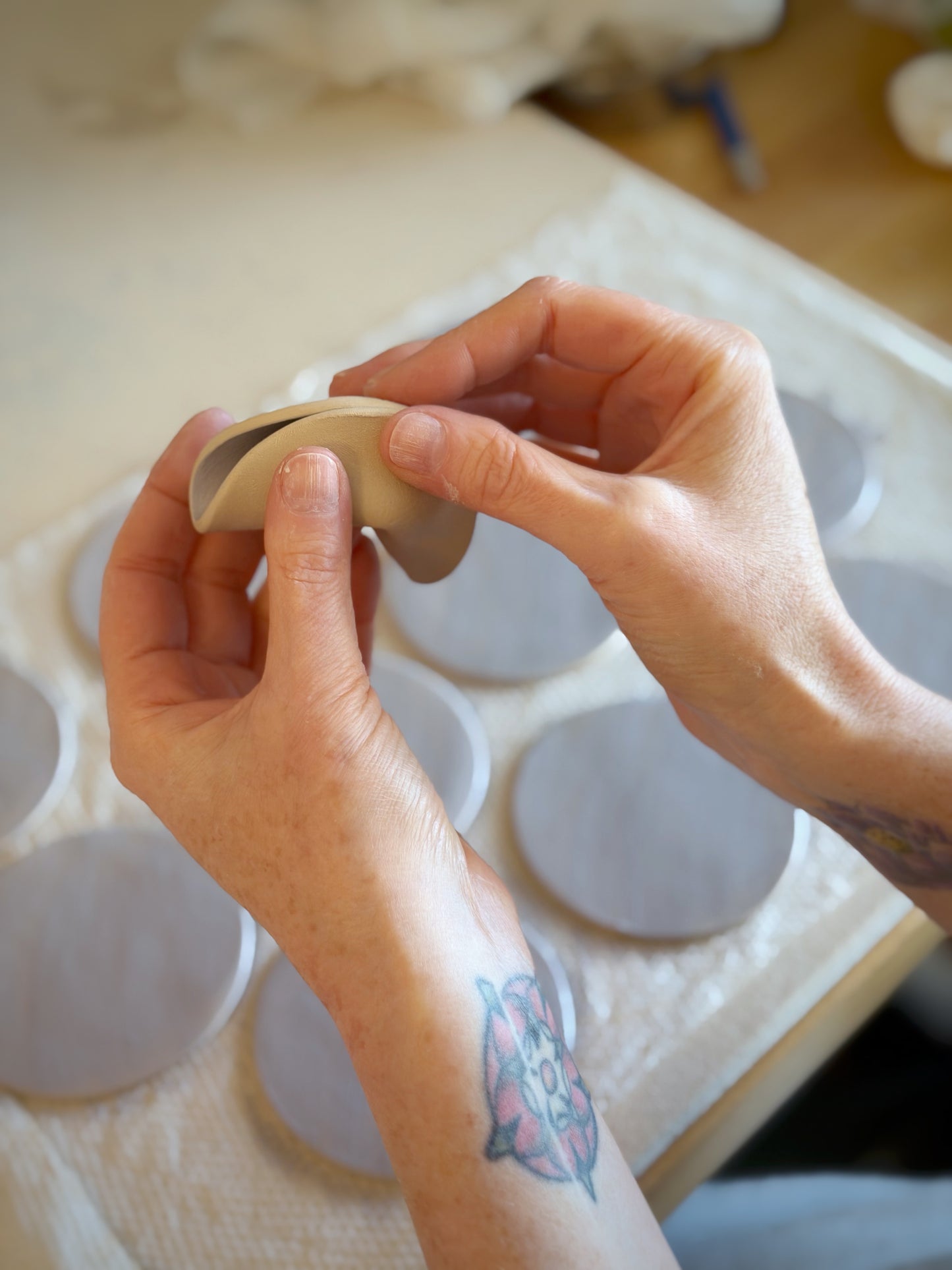 Close up of hands while making a clay fortune cookie by Kathleen Kalish Ceramics.