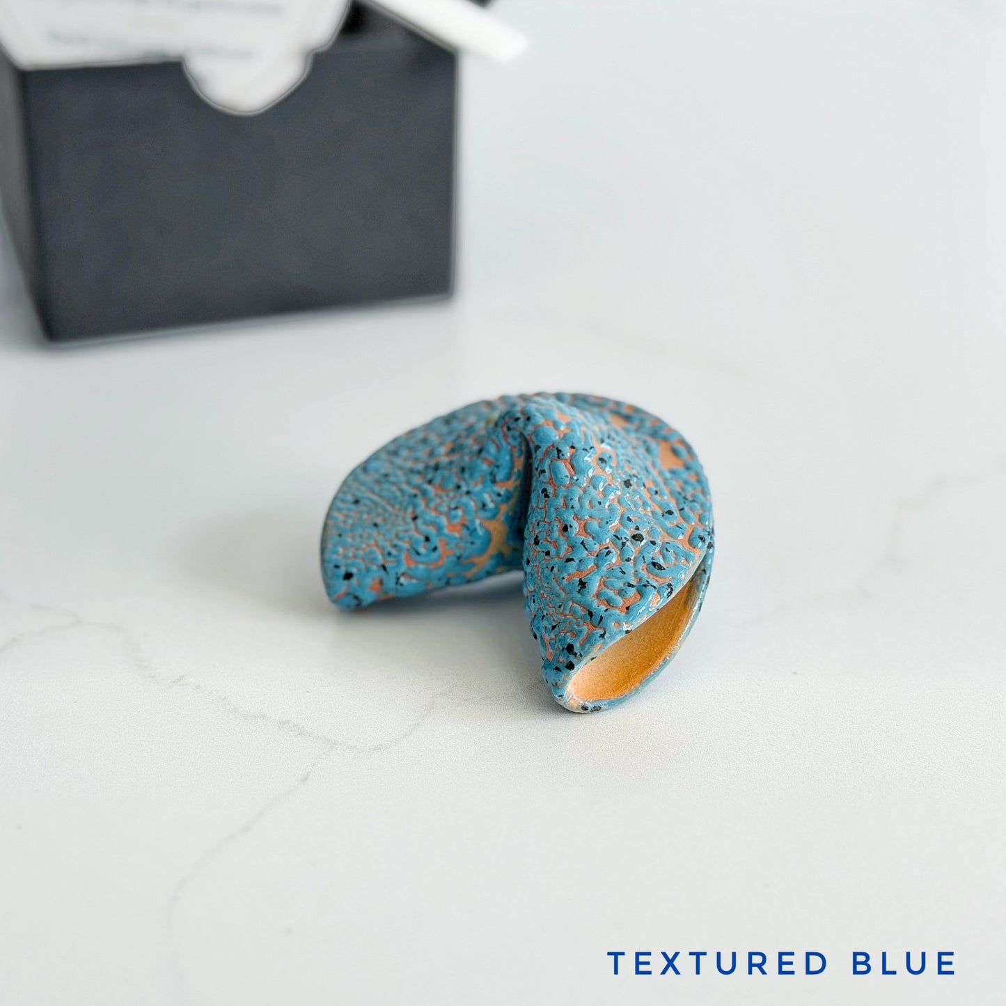 Textured pebbled blue ceramic fortune cookie, handmade and glazed by hand in Wilmington, NC by Kathleen Kalish Ceramics.